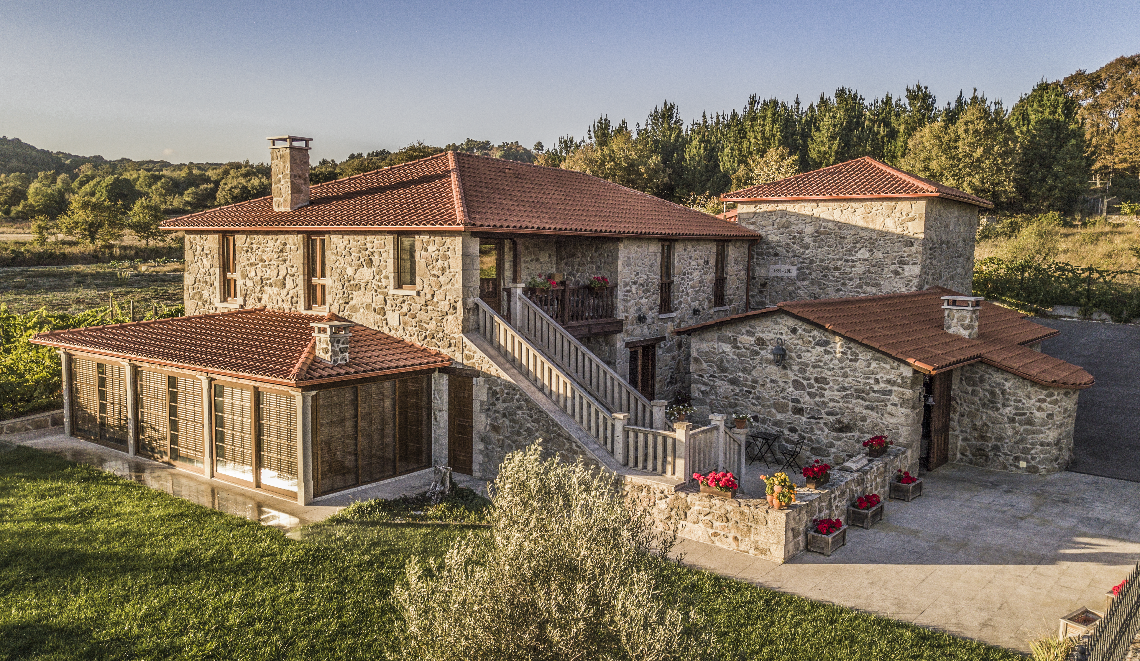 La fotografía principal de la casa de piedra de Ciudáseis, entre árboles y viñedo
