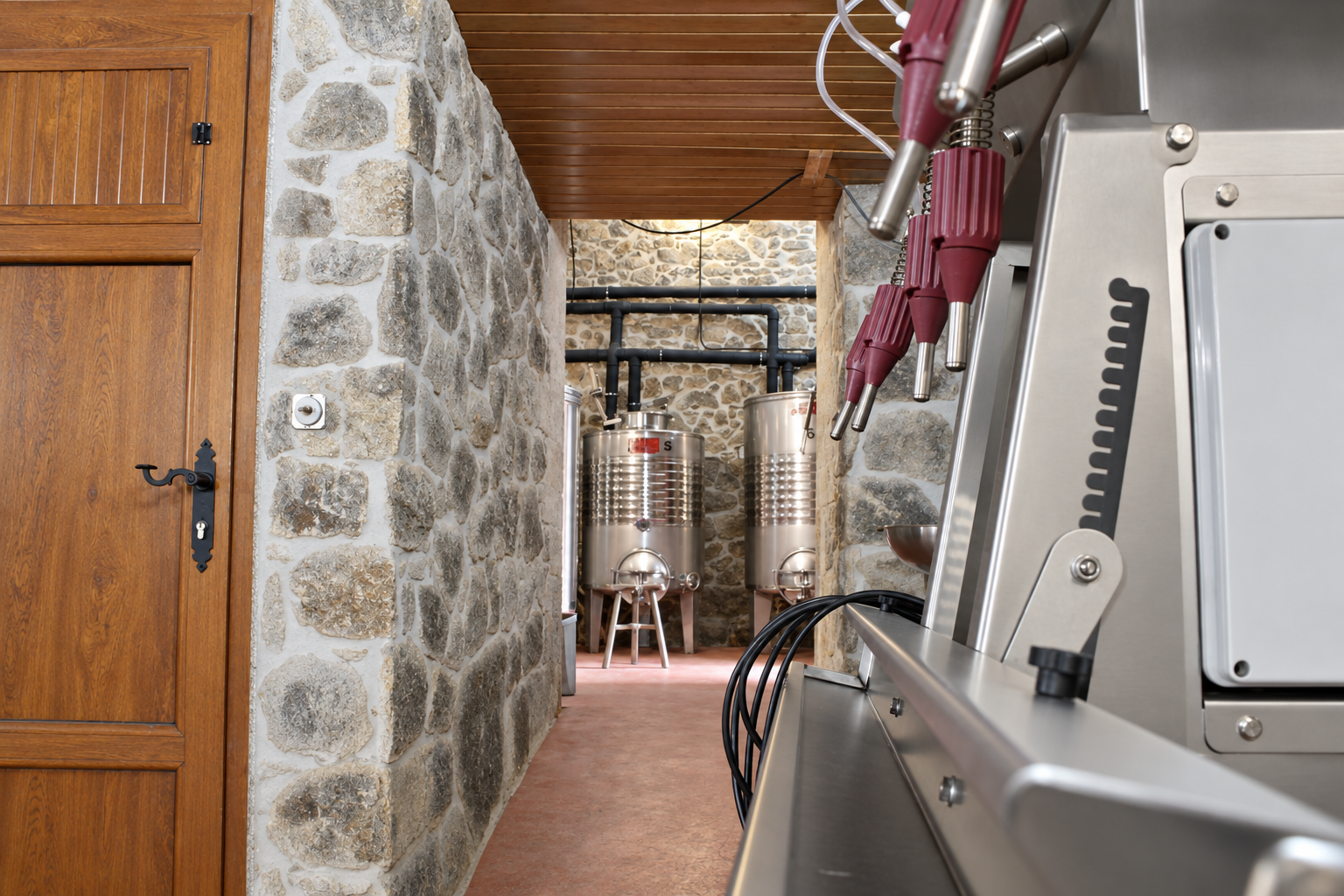 Interior de la bodega: muros de piedra, techo de madera, depósitos y embotelladora; fotografía retocada